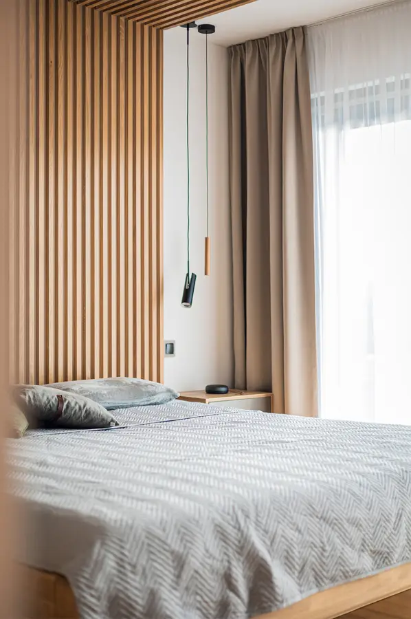 Ložnice s lamelovou stěnou a stropem jako hlavním motivem